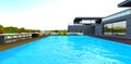 Large swimming pool near the suburban hotel with fenced terrace on the rooftop. Bar chairs on the decked floor. 3d rendering