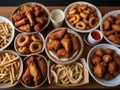 large table of assorted take out food such as pizza, french fries, onion rings, fried chicken and chicken wings