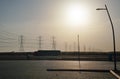 Large tall steel power pylons in rather flat landscape of Saudi Arabia, only black silhouettes visible against bright