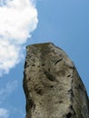 Large tall stone against blue sky with white fluffy clouds Royalty Free Stock Photo