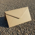 A large, tan envelope made from paperboard is placed on a gravel surface. The Royalty Free Stock Photo