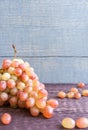 Tassel of yellow-red grapes is lying on dark wooden table on painted gray wooden planks background with copy space. Royalty Free Stock Photo