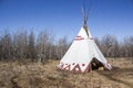 Large teepee sitting in a field of dead grass