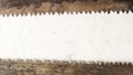 Large teeth of an old saw on wood. Sharp and uneven edges. Rusted surface. Light stone background. Royalty Free Stock Photo