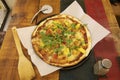 A large thin crust pizza with pineapple, cherry tomatoes