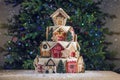Large tiered Christmas cake decorated with gingerbread cookies and a house on top. Tree and garlands in the background. Royalty Free Stock Photo