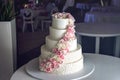 A large tiered wedding cake decorated with pink roses on the table in the restaurant