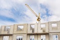 A large tower crane builds a house against a blue sky with clouds. Construction of an apartment building Royalty Free Stock Photo