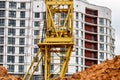 A large tower crane at a construction site against the backdrop of a modern monolithic house. Modern housing construction. Royalty Free Stock Photo