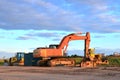 Large tracked excavator and bulldozers on a construction site, background of the sunset.