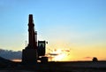 Large tracked excavator on a construction site against the background of the awesome sunset. Road repair, asphalt replacement. Royalty Free Stock Photo