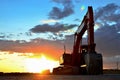 Large tracked excavator on a construction site against the background of the awesome sunset. Road repair, asphalt replacement. Royalty Free Stock Photo