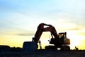 Large tracked excavator on a construction site on the awesome sunset background. Road repair, asphalt replacement Royalty Free Stock Photo