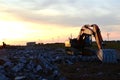 Large tracked excavator on a construction site on the awesome sunset background. Road repair, asphalt replacement. Royalty Free Stock Photo