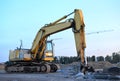 Large tracked excavator with with hydraulic hammer breaks asphalt at a construction site against on the background sunset. Road Royalty Free Stock Photo