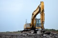 Large tracked excavator with hydraulic hammer breaks asphalt at a construction site on the background sunset Royalty Free Stock Photo