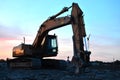 Large tracked excavator with hydraulic shears on a construction site against the background of the awesome sunset. Royalty Free Stock Photo
