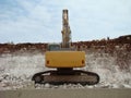 A large tracked excavator works to dig up rocks for the road