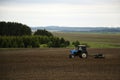 Large tractor with plow plows field before spring sowing of crops. tractor with harrow drives across plowed field and levels