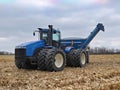 Large tractor pulling a grain cart in a harvested corn field