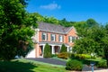 Large traditional American single family home with beautiful landscaping and lawn. Summer landscape on a sunny day under a blue