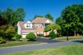 Large traditional American single family home with beautiful landscaping and lawn. Summer landscape on a sunny day under a blue Royalty Free Stock Photo