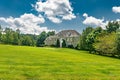 Large traditional American single family home on a large wooded lot in Virginia. Summer landscape on sunny day under cloudy sky Royalty Free Stock Photo
