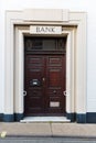 A large traditional double wooden security door with a sign for the bank above