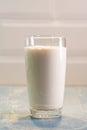 A large transparent glass of milk standing on a blue wooden table in the kitchen. Dairy product. Royalty Free Stock Photo