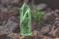 Large transparent mystical faceted crystal of colored green emerald quartz on a stone background close-up. Wonderful mineral