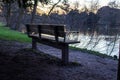 A large tree, a bench, a mountain range stand out as a silhouette from the blue-golden, lightly clouded evening sky, which is Royalty Free Stock Photo