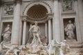 Large Trevi Fountain adorns the exterior of a modern building, its features illuminated by the sun