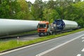 A large truck is driving along the highway, carrying a cylindrical load.