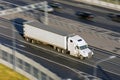 Large truck with a trailer on the highway at a speed that moves along the asphalt, evening sunset light. View from above. Royalty Free Stock Photo