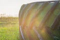 Large truck wheel tire on the grass under grey sky with lens flare Royalty Free Stock Photo