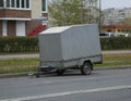 Large two-wheeled gray awning trailer for a passenger car parked on the street