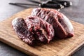 Large uncut pieces of raw beef shank on a chopping board with knives in the background