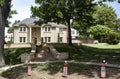 Large upscale brick house in leafy neighborhood with firecracker 4th of July ornaments in front