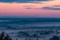 A large valley, covered with fog and illuminated by a scarlet sunset.