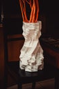 A large vase printed on a 3d printer stands on a chair in an interior close-up
