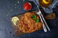 Large Viennese schnitzel on a black background. Meat dish.