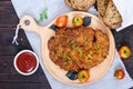 A large Viennese schnitzel on a cutting board on a dark wooden background.