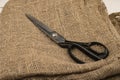 Large vintage sartorial scissors on a background of coarse-textured burlap. Close up