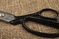 Large vintage sartorial scissors on a background of coarse-textured burlap. Close up