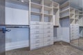 Large walk-in closet with white shelves, drawers Royalty Free Stock Photo