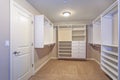 Large walk-in closet with white shelves, drawers Royalty Free Stock Photo