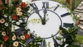 Large wall clock on the field in blooming flowers, showing the time 11:55, 12:00. time management concept, daylight Royalty Free Stock Photo