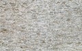 Large wall made of small natural stone bricks. Color is light gray with brown stains. Royalty Free Stock Photo