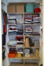 Large wardrobe closet with neatly folded different clothes, home stuff and boxes.