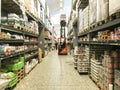 Large warehouse wholesale with rows of aisles and shelves from floor to ceiling. Forklift lifting boxes to the upper shelves.